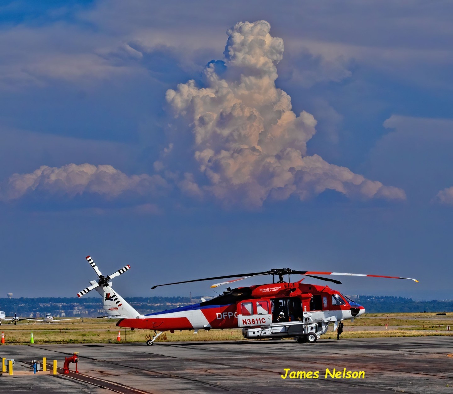 State of Colorado Firehawk sits on ramp in front of the State of Colorado hanger a Metro Airport with a building thunderstorm building in the distance.