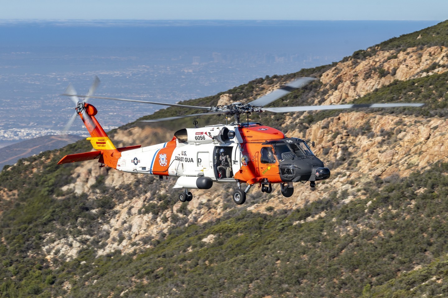 I did a special shoot of the United State Coast Guard Sikorsky MH-60T Jayhawk helicopter on the Otay Mountains in San Diego County, California. We got permission to drive on a BLM land dirt road which got me near the top of mountain. I then hiked up a brush filled hill to get to the right location. The road driving up was very bumpy and close to extremely steep drop offs. In the background are the cities of Otay Mesa and San Diego, California.