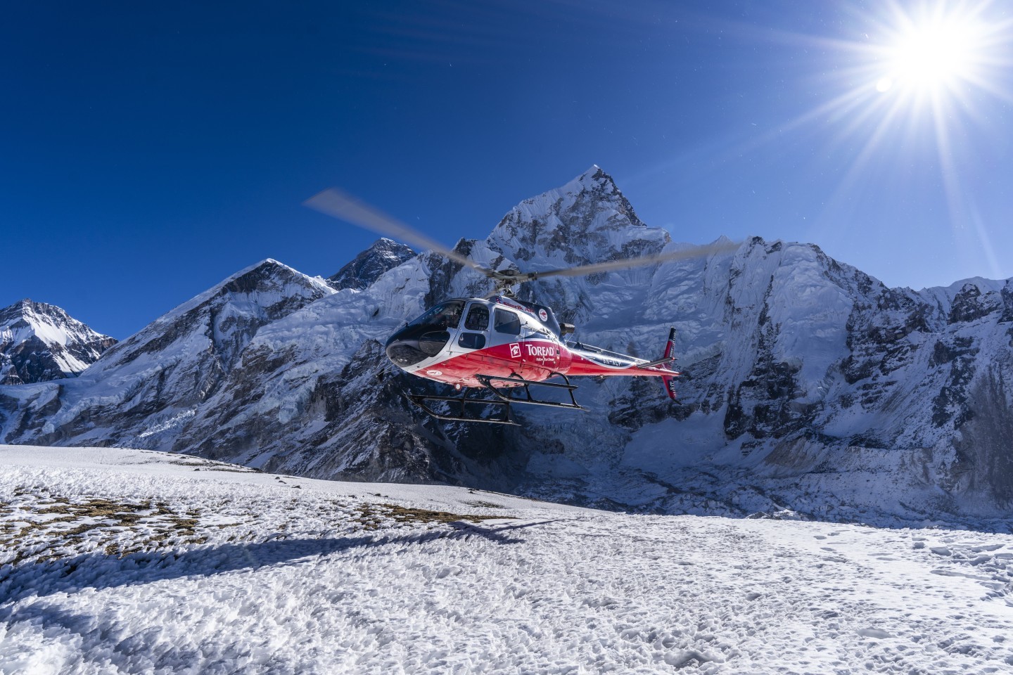 Photo of a helicopter taking off from Kalapattar, a mountain in Everest Region of Nepal with an elevation of 5600m, during a mountain flight around a mountain in Everest Region of Nepal. Everest Clearly seen in the background.