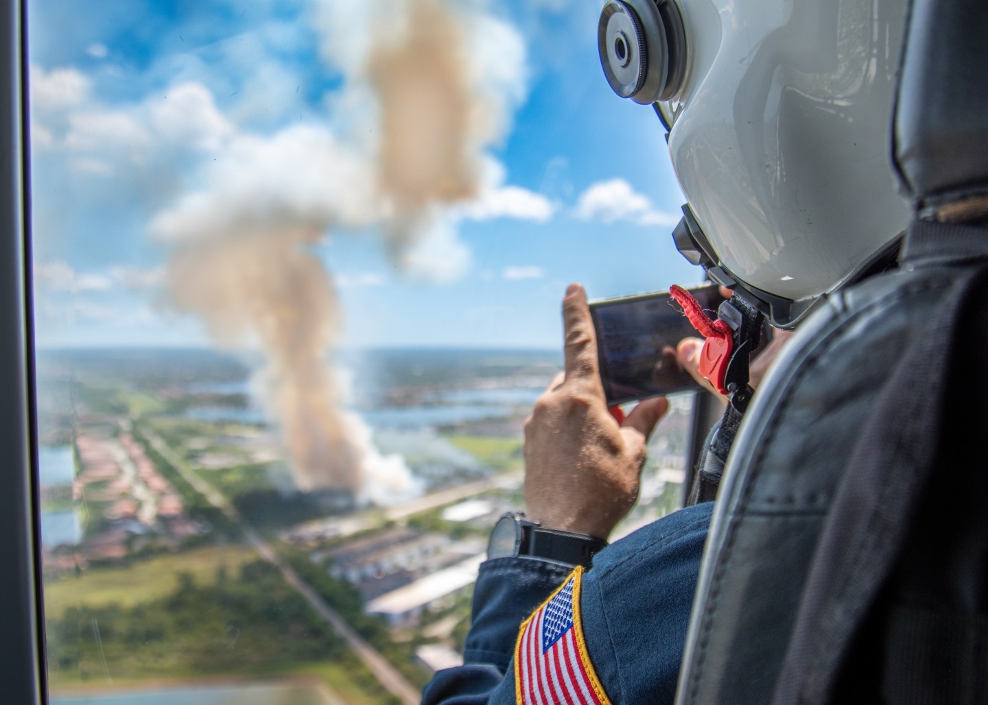 A Miami Dade Fire Rescue firefighter/paramedic snaps some real time pictures from the air to ground support units fighting a rapidly developing brush fire near Miami Excecutive Airport.