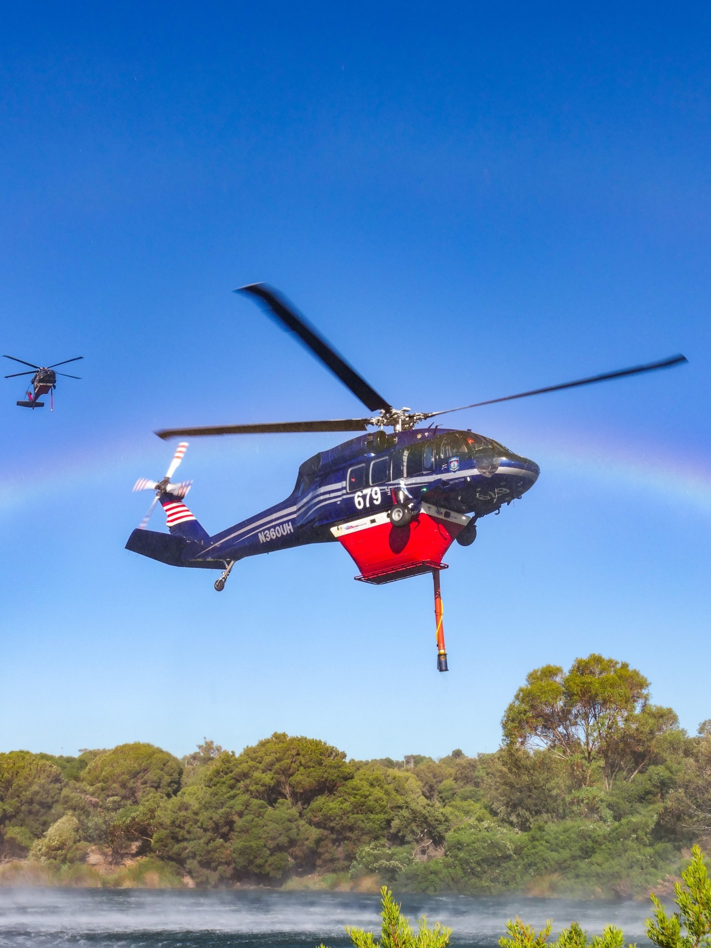 Two Black Hawk helicopters, aircraft 679 and 678, can be seen in the background supporting firefighting efforts during the bushfire near Falcon. The helicopters were operating as part of the aerial firefighting response, using their speed and lifting power to deliver large volumes of water directly onto the fire front.

To refill, the Black Hawks were drawing water from The Cut Golf Course, which provides a large, reliable water source close to the fire ground.
