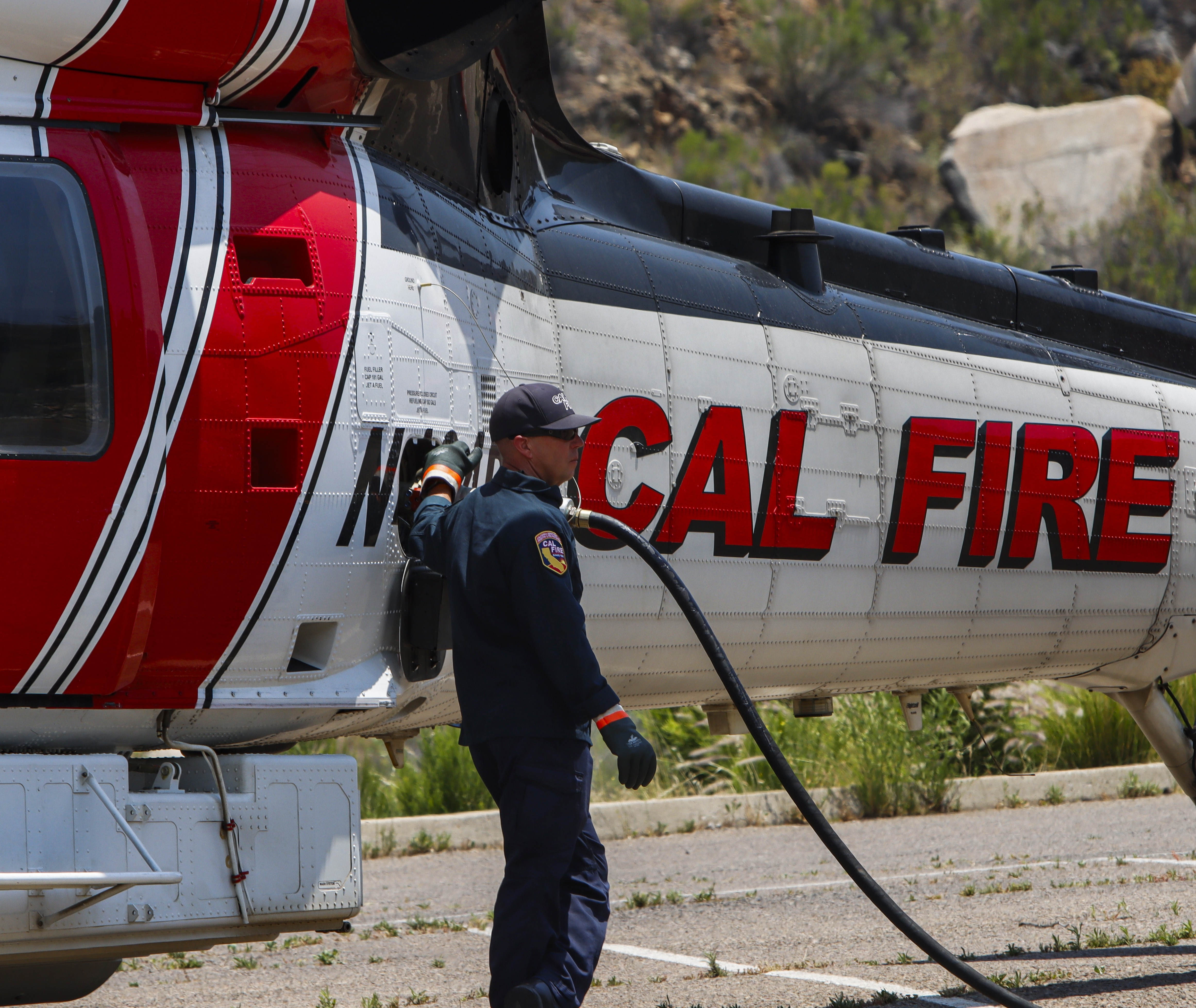 A CAL FIRE crewmember fills up their Sikorsky S-70 Firehawk shortly after landing at a staging area in Lakeside, CA during the Monte Fire in June 2025.
