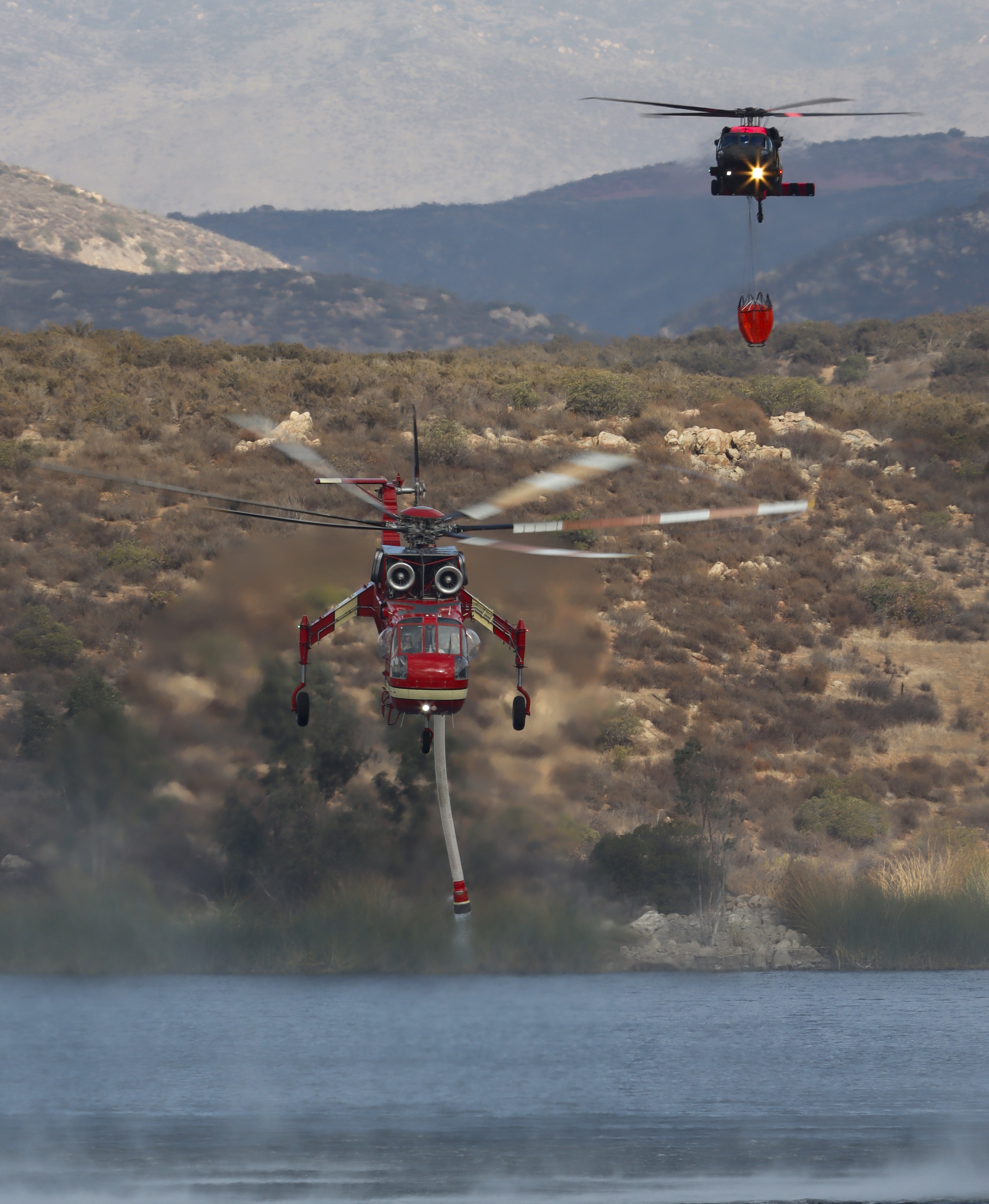 Siller Helitanker 95B shadowed by Army Nat'l Guard Copter 836, while departing Otay Lakes in Chula Vista, CA during the Border 2 Fire burning in the Otay Mountain Wilderness.