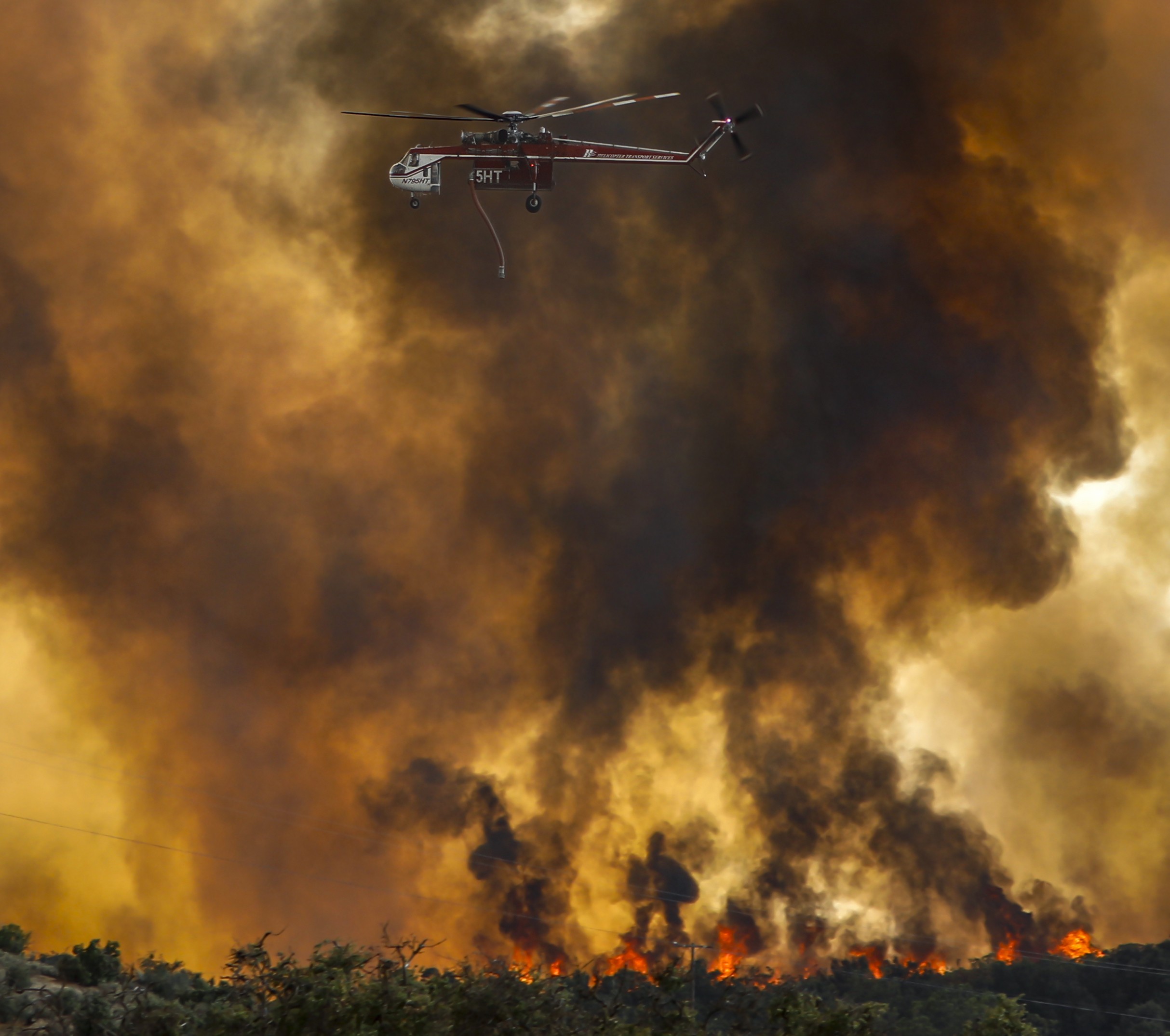 Helicopter Transport Services (Canada based operator) Helitanker 5HT, passes over an active uncontrolled wall of fire during the Dale Fire in Riverside County, CA..