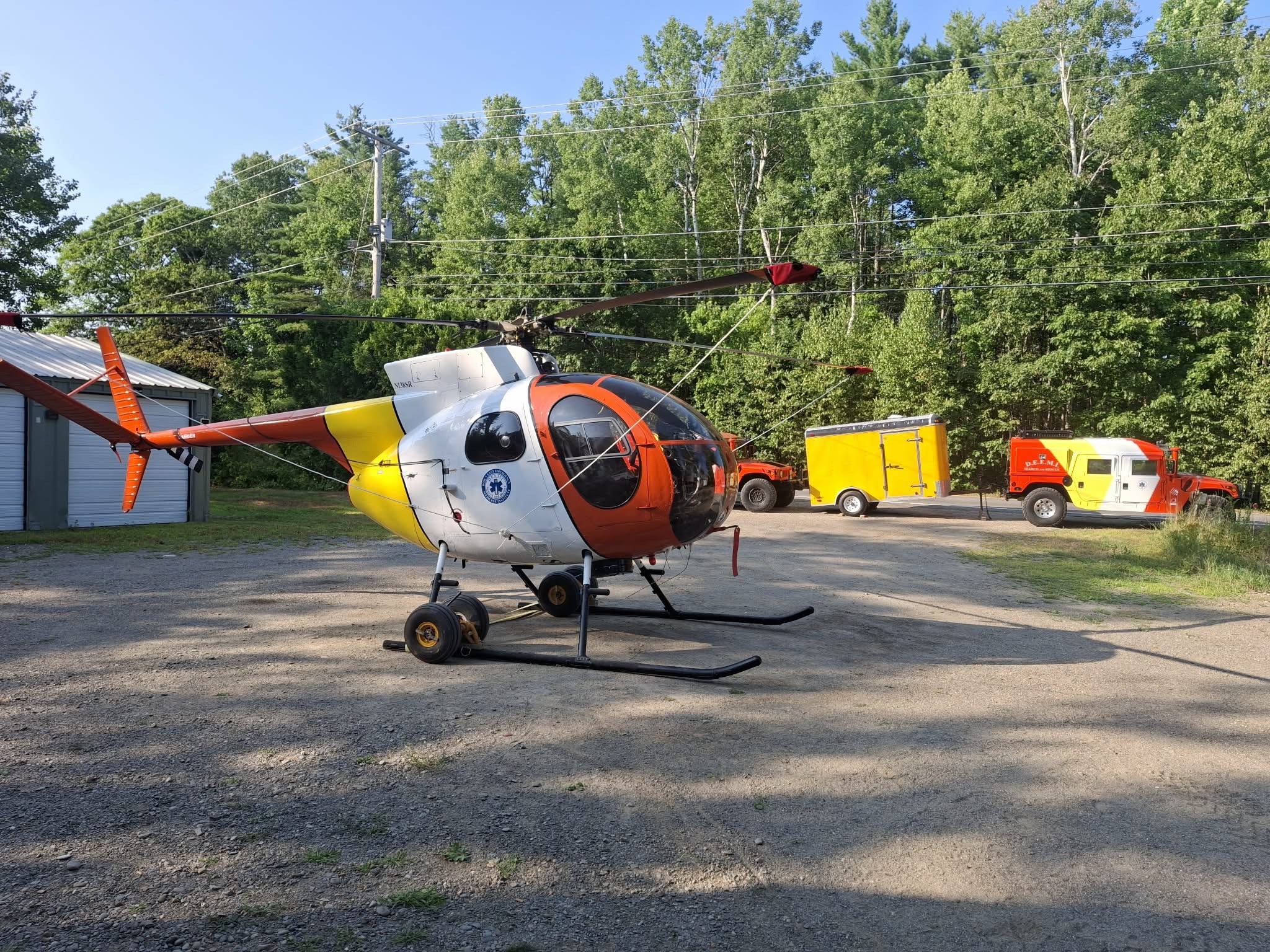 Search and rescue aircraft at rest at the rescue station with sar hmmwv note color scheme in high vis for crew safety and finding units in the Maine woods
