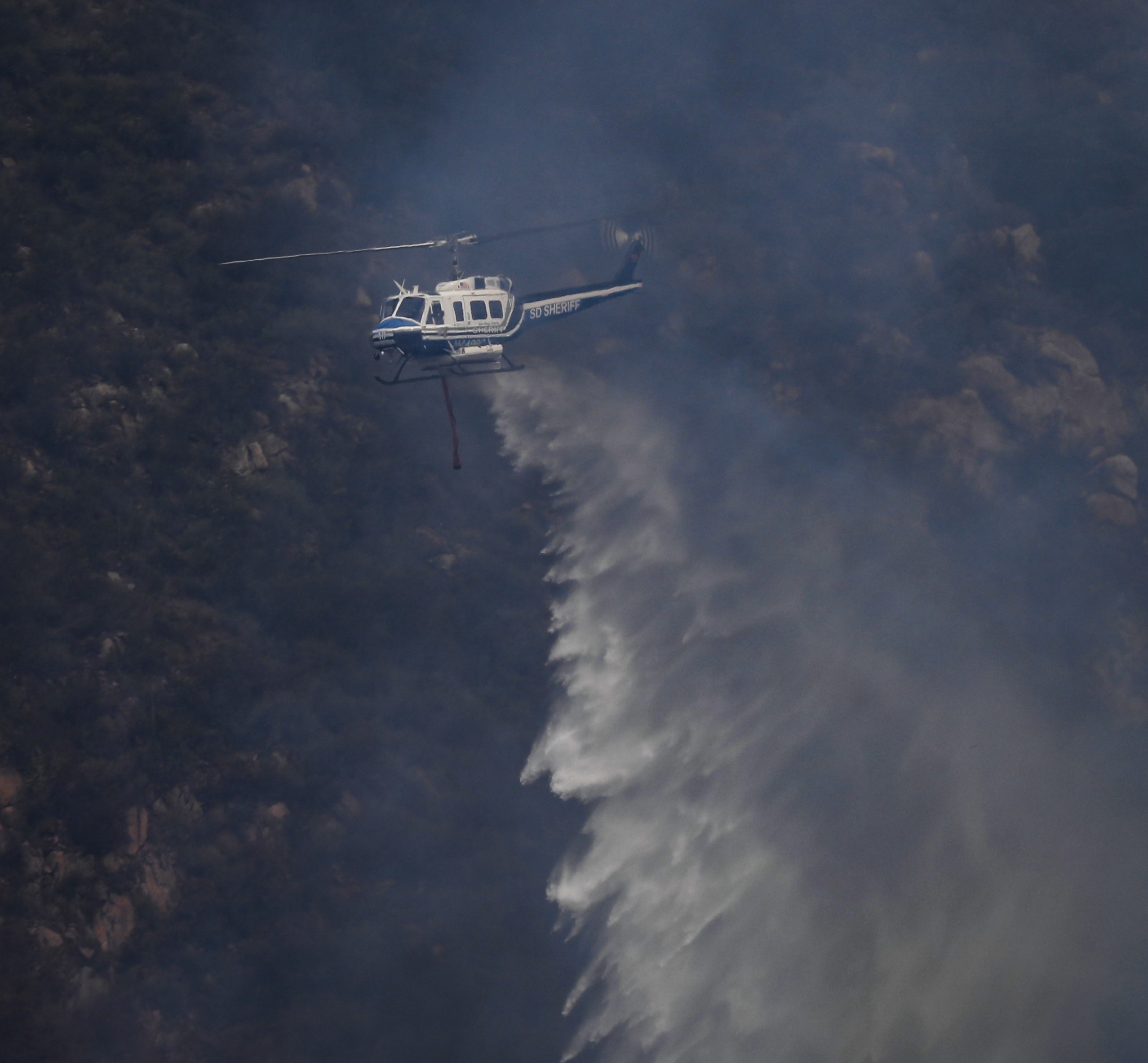 Copter 10 from the San Diego County Sheriff's Dept. dropping water on hot spots part of a large vegetation fire operation during the Henderson Fire in Pala, CA of San Diego County.