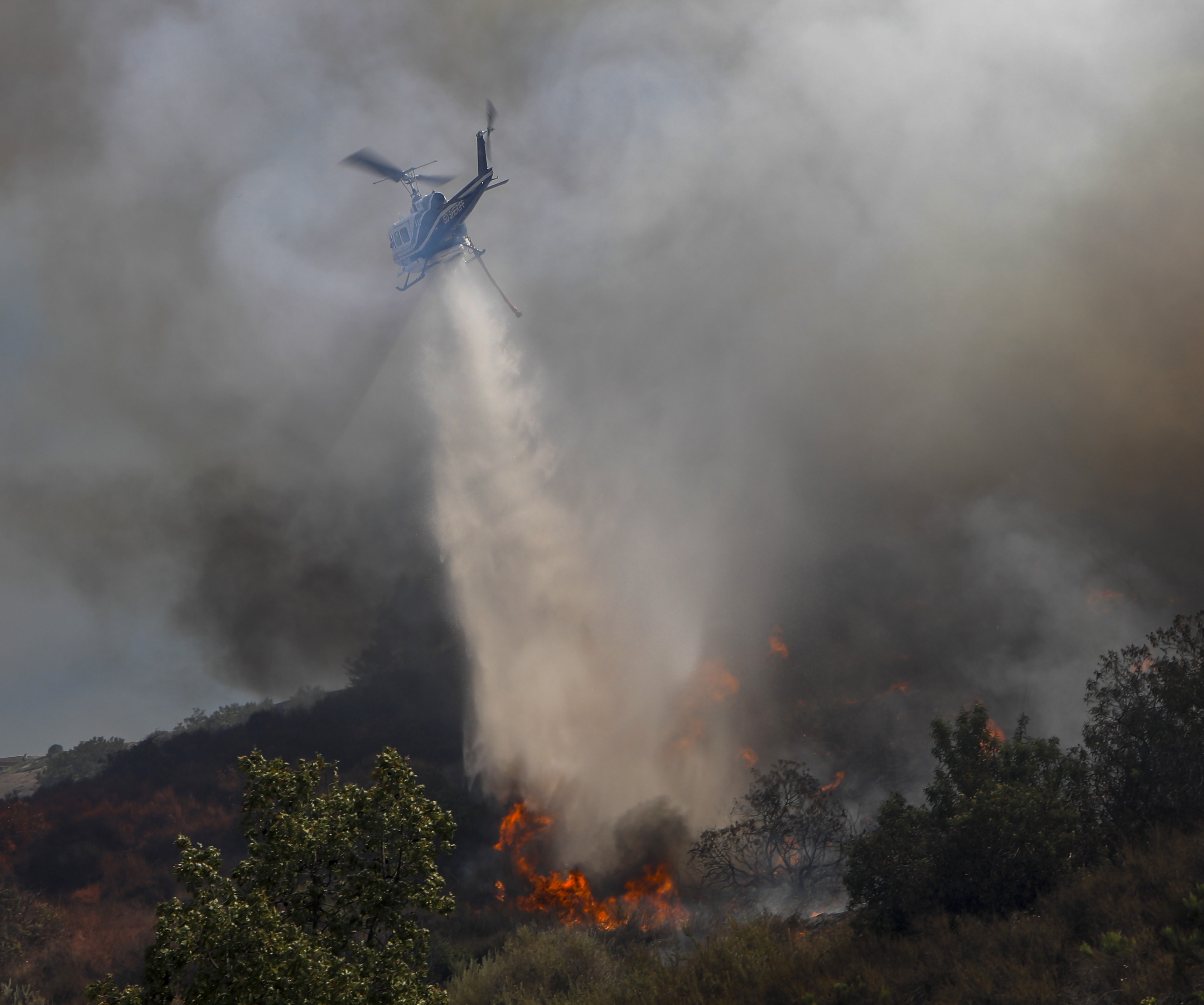 Copter 10 from the San Diego County Sheriff's Dept. dropping water on an active flame during a moderate sized vegetation fire dubbed the Steele Fire in Jamul, CA of San Diego County.