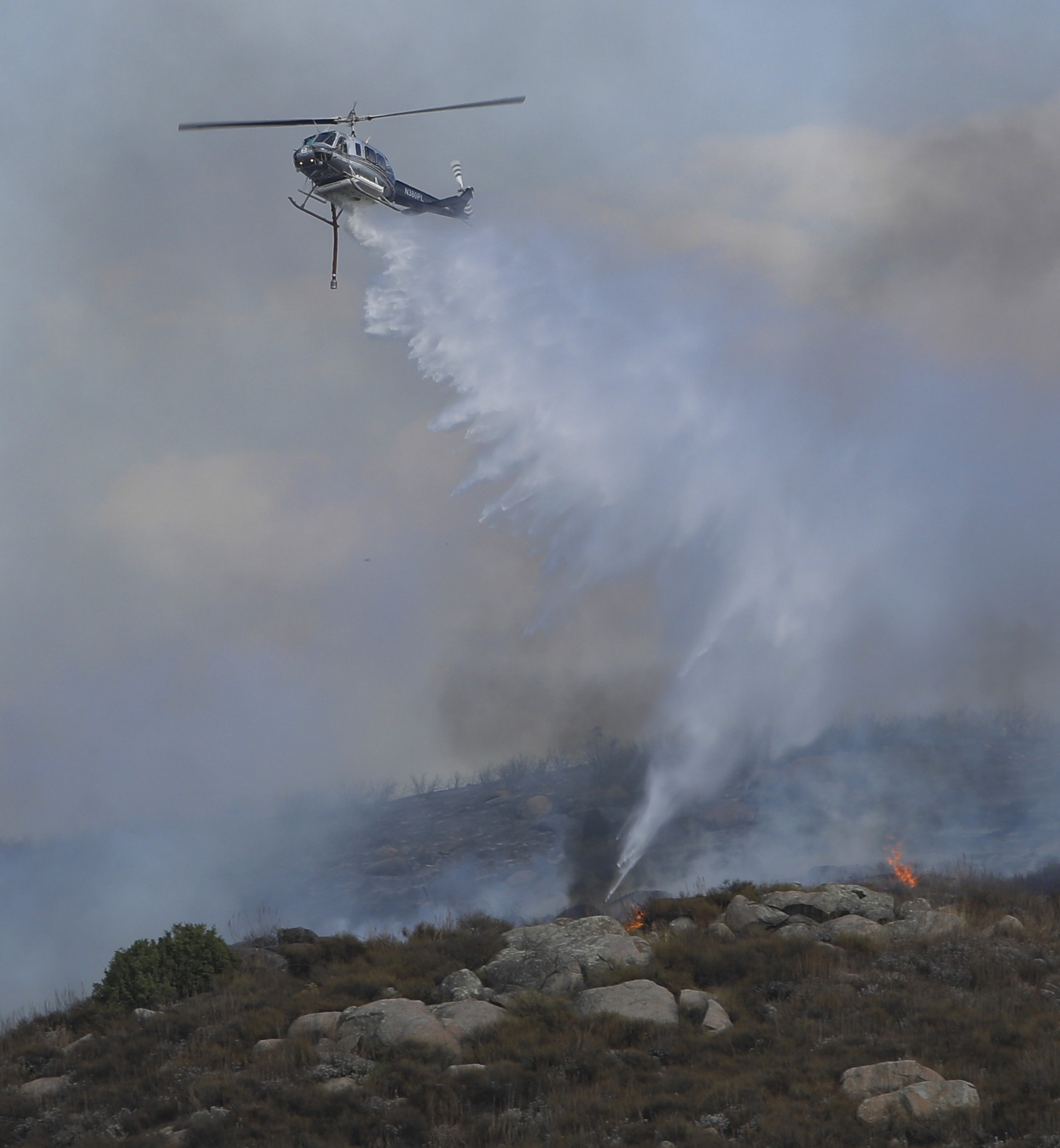 Ramona Helitack 538 flown by the United States Forest Service, dropping water on a moderated sized vegetation during the Rancho Fire burning east of Ramona, CA in San Diego County.
