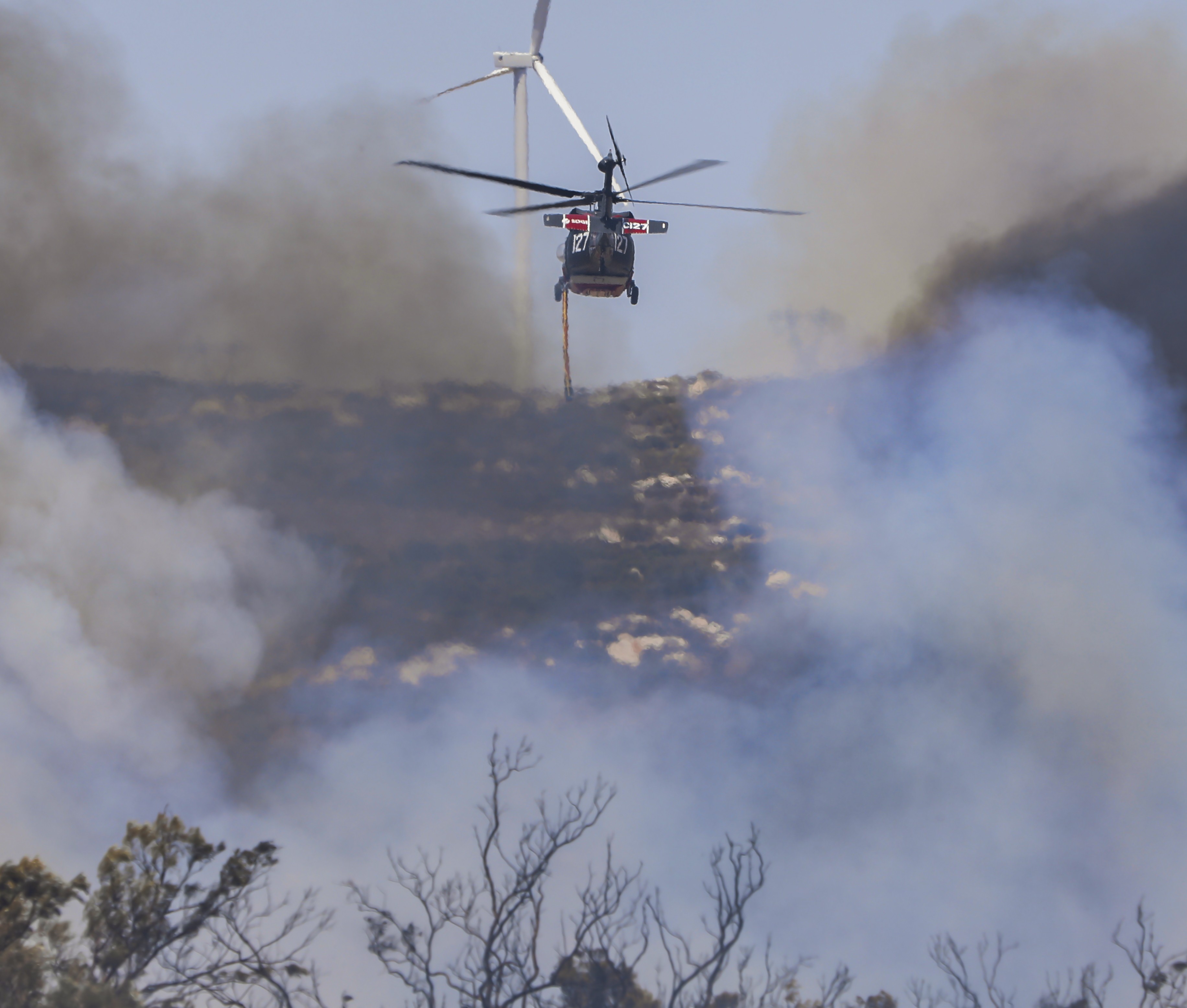 Copter 127 operating as a private contractor assigned to San Diego County during the fire season, passes through a column of dense smoke during the Road Runner Fire in Boulevard, CA.