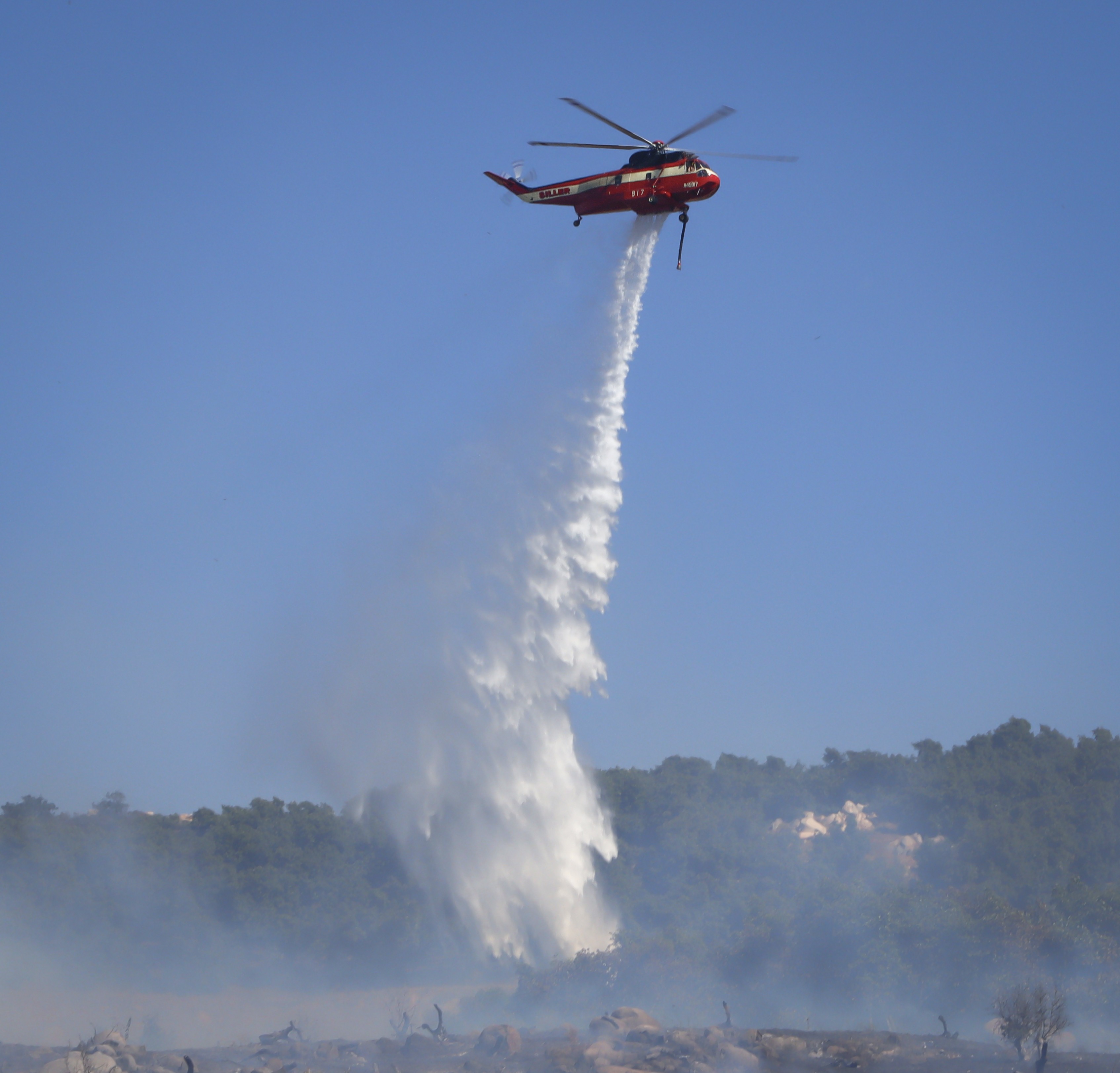 Siller Helicopters Helitanker 917, dumping loads of water onto vegetation from a 50-acre vegetation fire in the urban interface during the Hawick Fire in Lakeside, CA.
