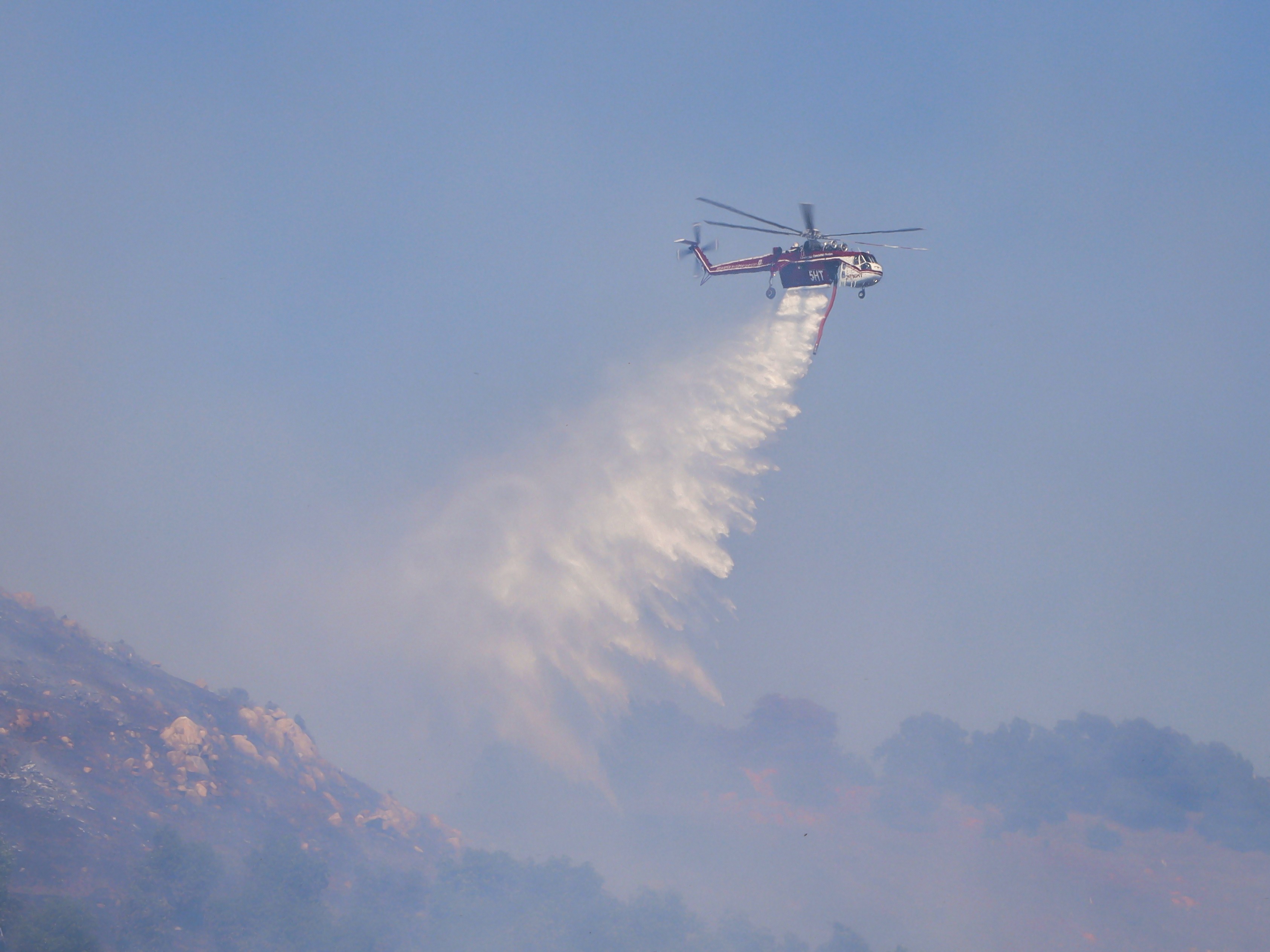 Helicopter Transport Services Helitanker 5HT, dumps its load of water on a 50-acre vegetation fire in the urban interface during the Hawick Fire in Lakeside, CA.