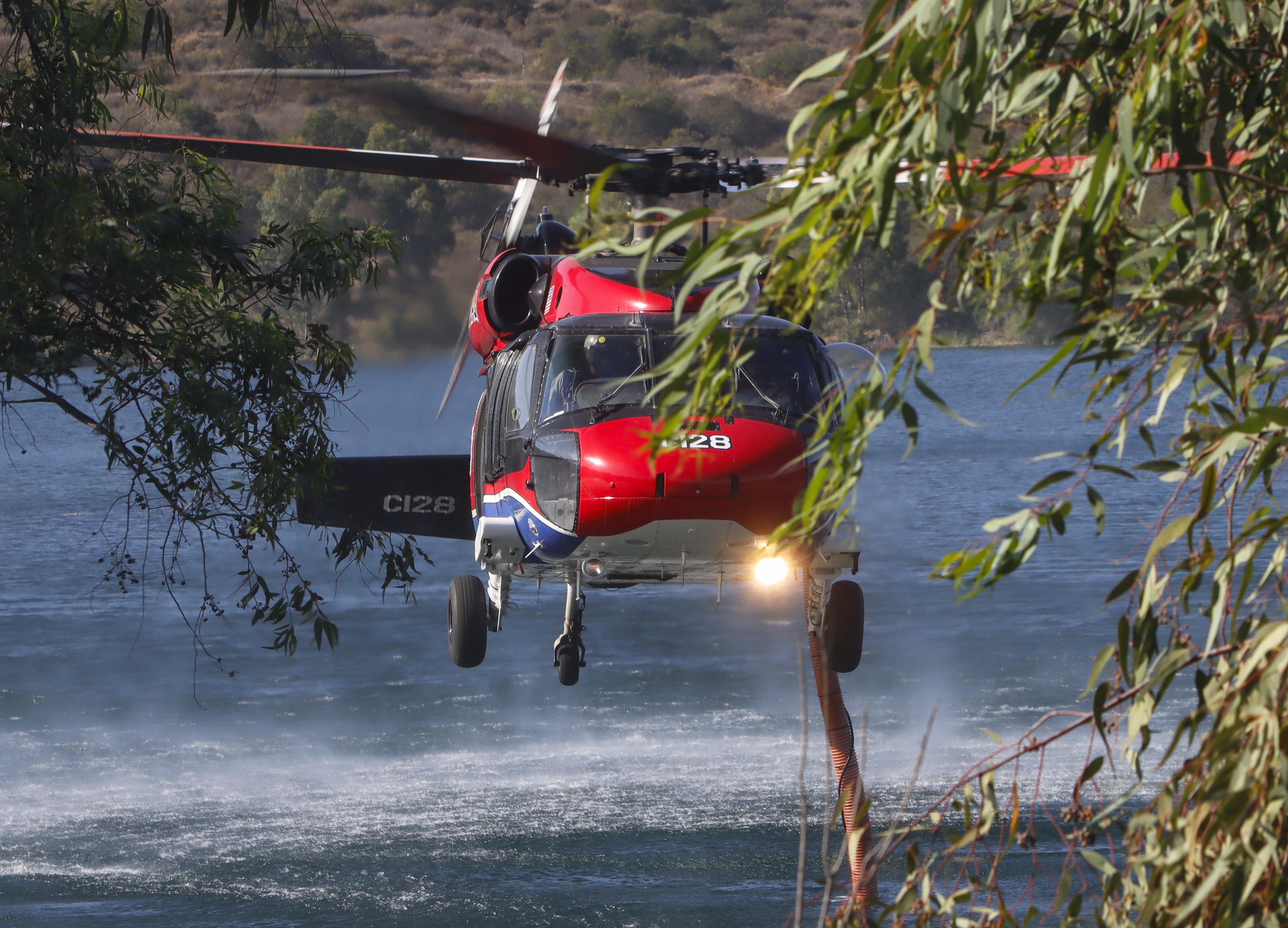 Copter 128 from a private contracting company, holds a perfect hover while in the dip at Lake Jennings during the Hawick Fire burning in Lakeside, CA.