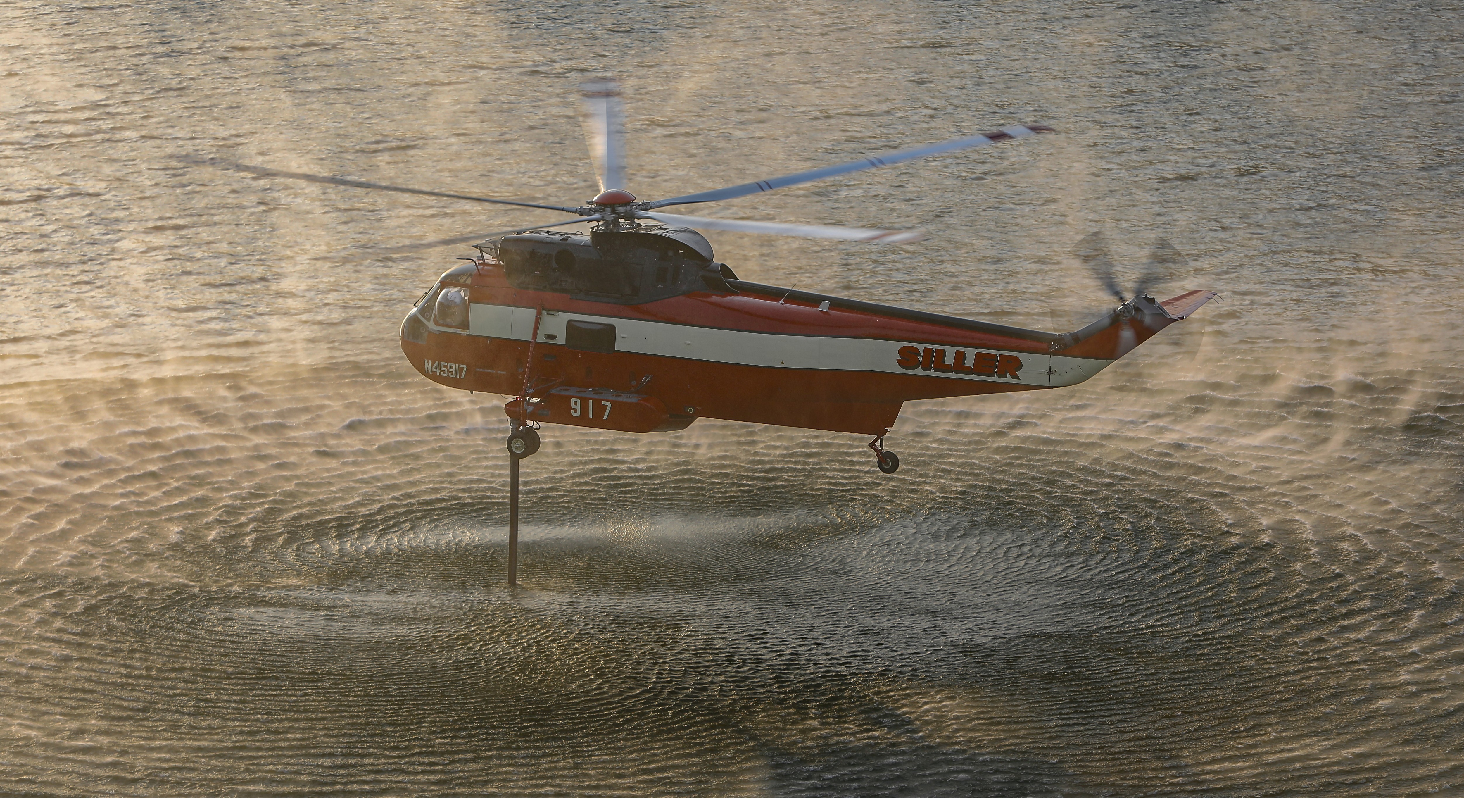 During golden hour in Lakeside, CA a Siller Helicopter Helitanker 917 uploads gallons of much needed water from the El Capitan reservoir during the Monte Fire.