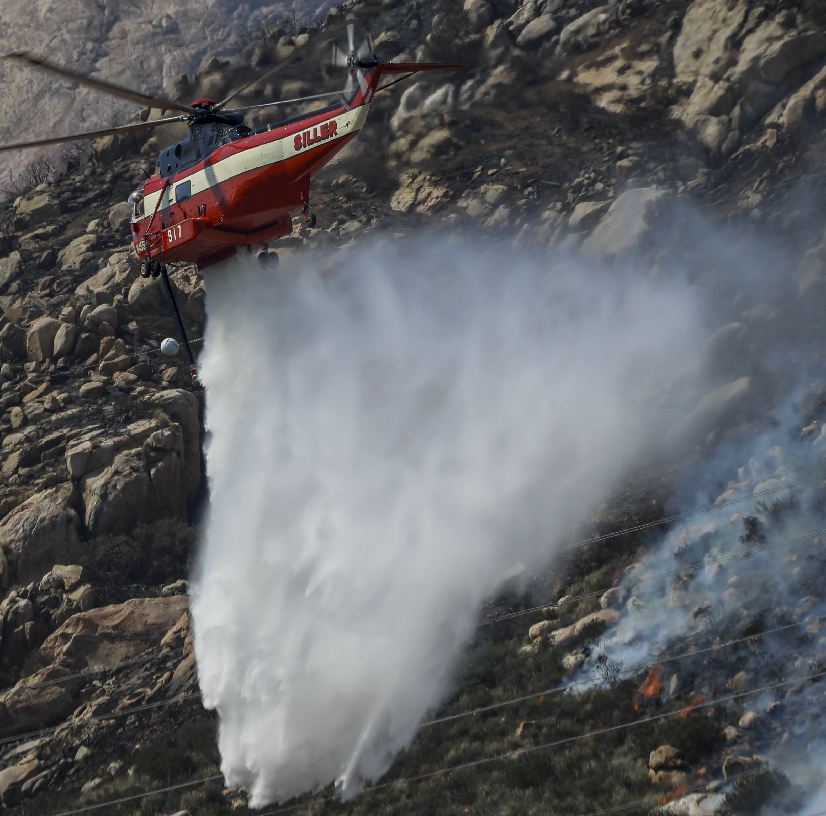 While supporting aerial firefighting operations, a Siller Helicopters Helitanker 917 dumps thousands of gallons of water supporting the FF on the ground during the Monte Fire