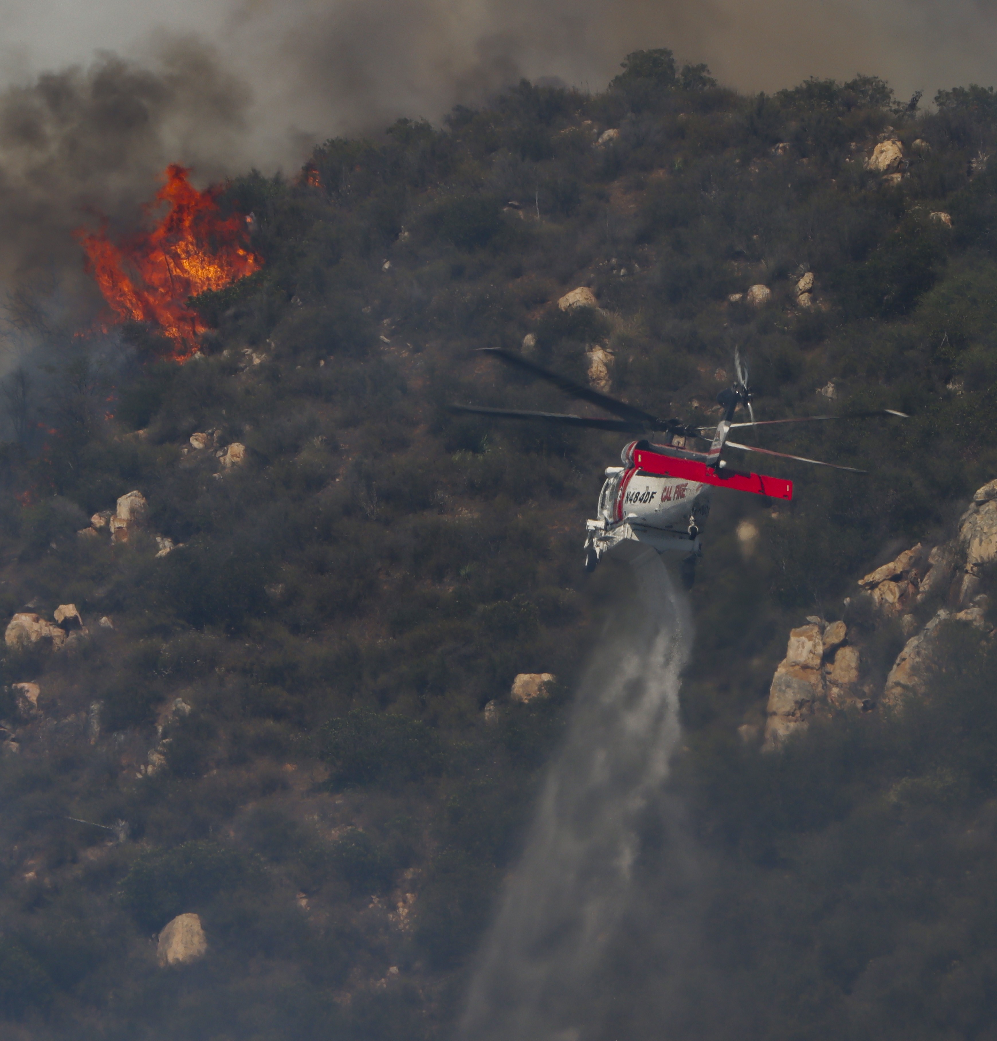 CAL FIRE Copter 609, actively fighting active flames in dense vegetation supporting other firefighting agencies with containing a large vegetation fire in Lakeside, CA dubbed the Monte Fire.