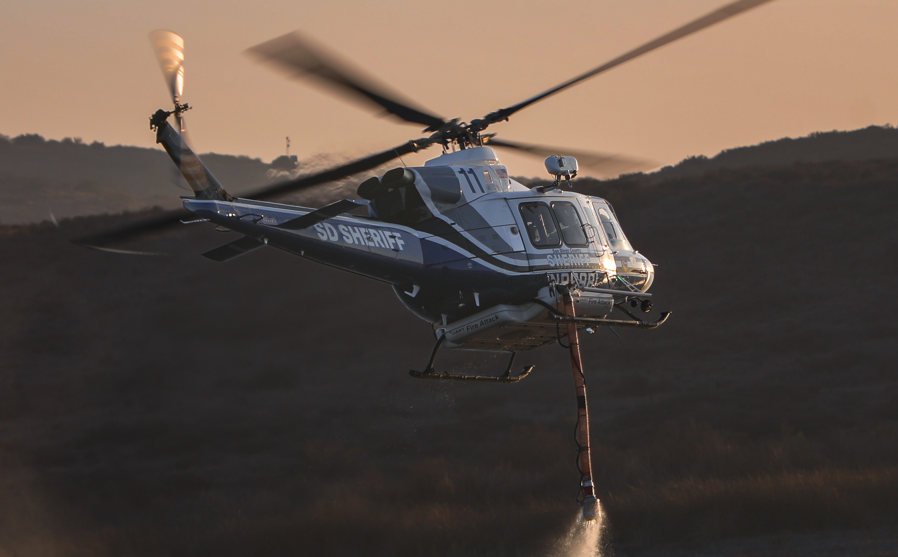 During golden hour, Copter 11 from the San Diego County Sheriff's Dept, departs the Lower Otay Lakes in Chula Vista, CA while supporting aerial firefighting operations during the Border 18 Fire in the Otay Mountain Wilderness.
