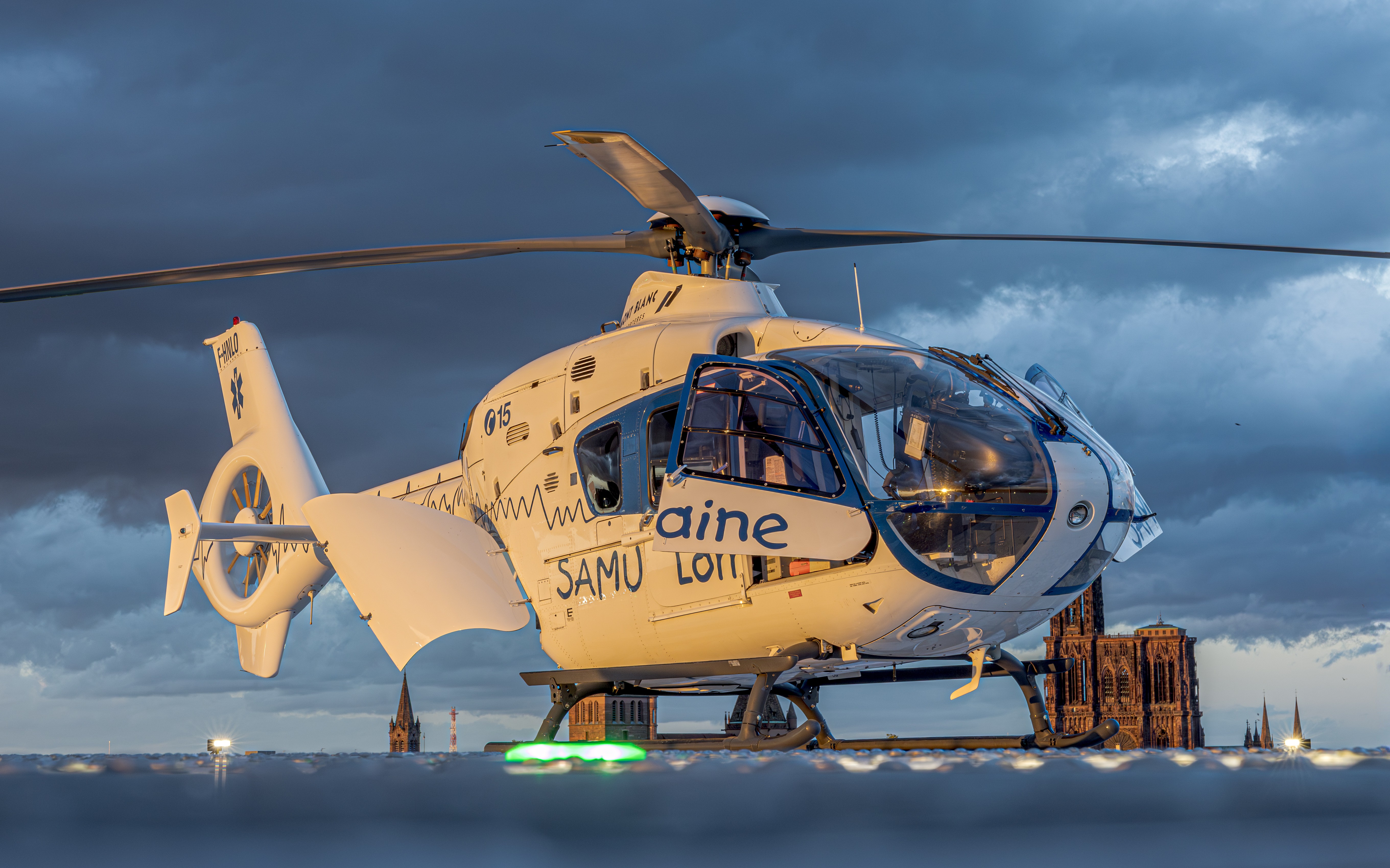 EC135 SAMU Lorraine on the FATO at Strasbourg University Hospital, last sun rays with the cathedral behind, for a transplant patient.